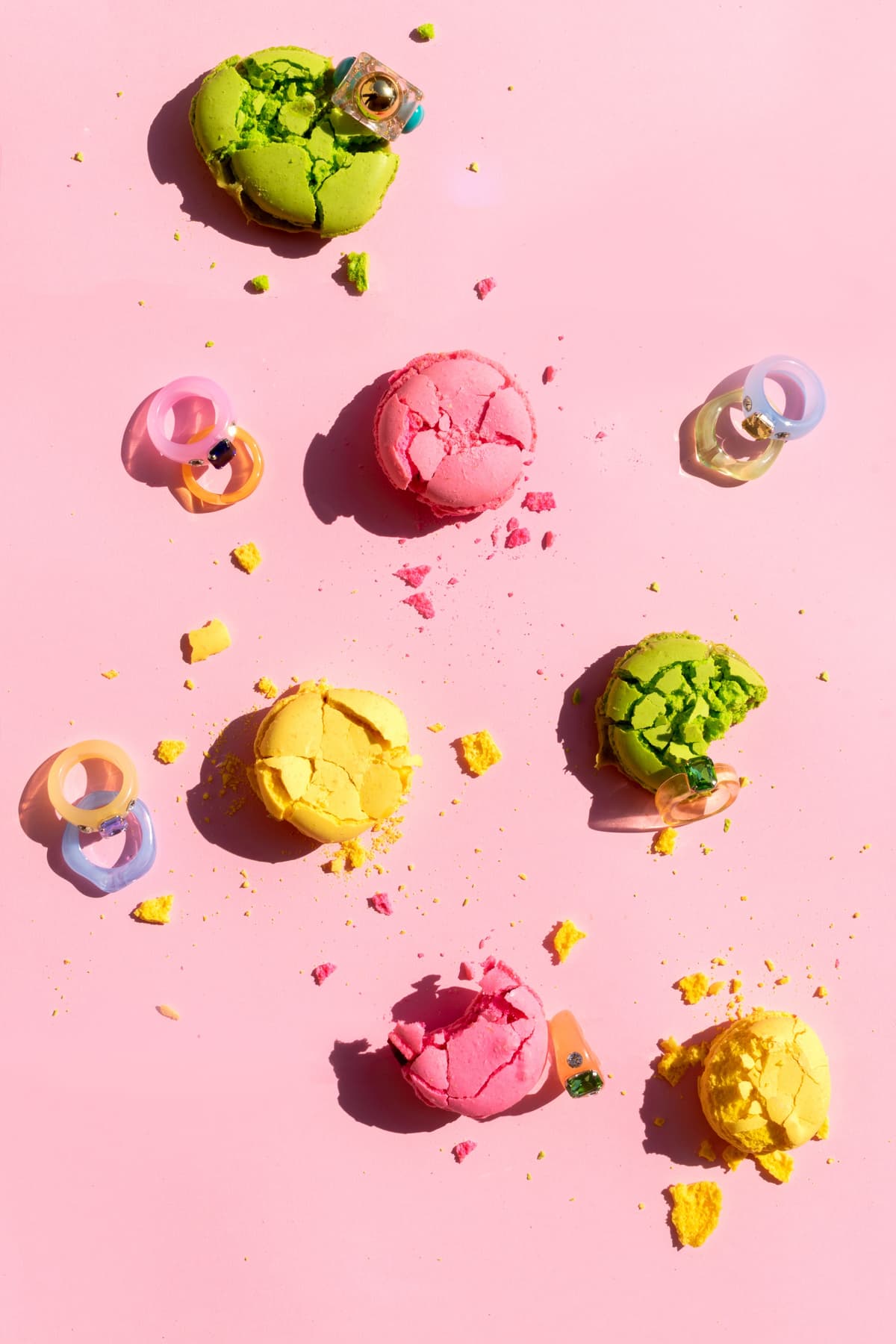Colorful macarons with rings on pink background