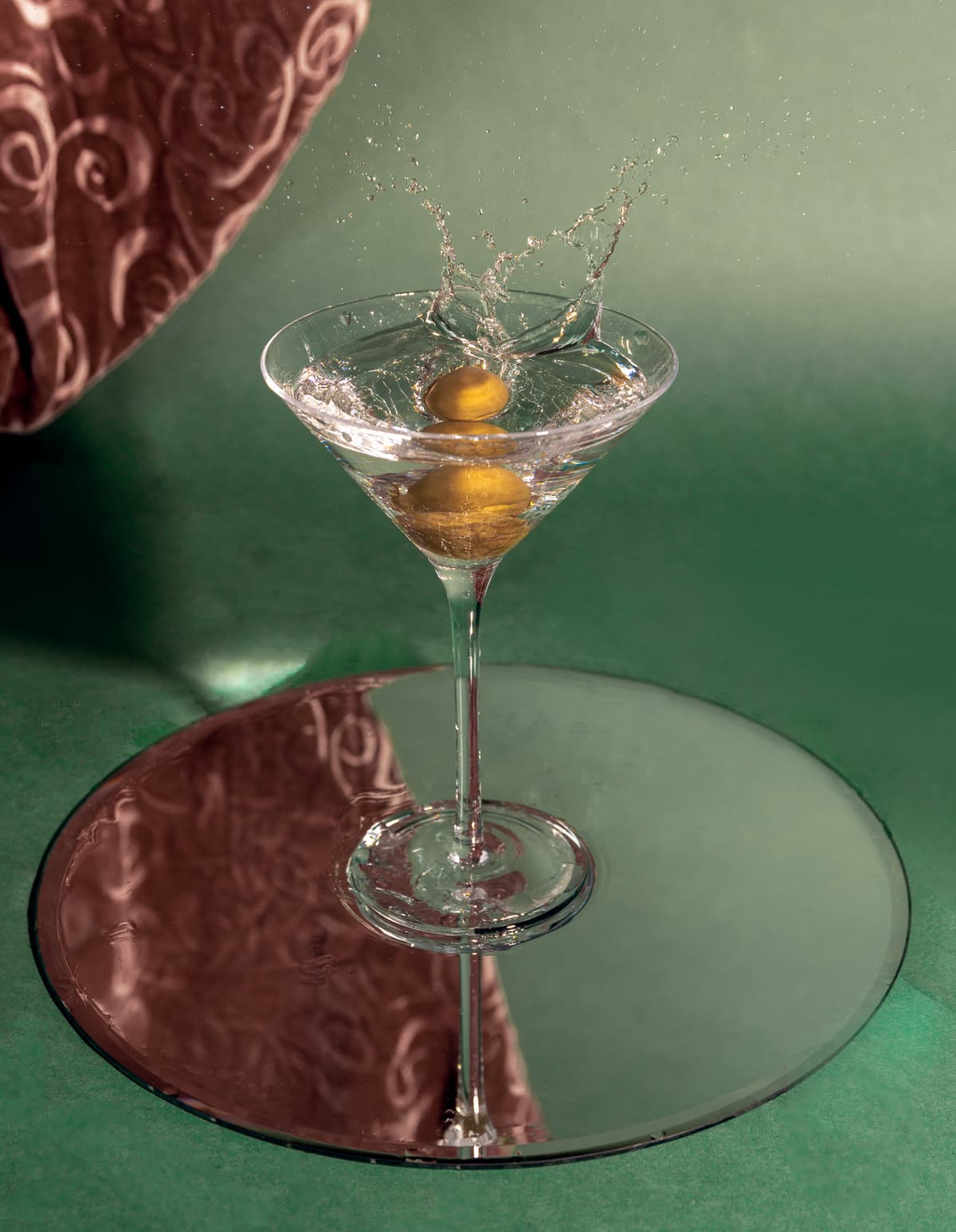 Martini glass with olive splash on green